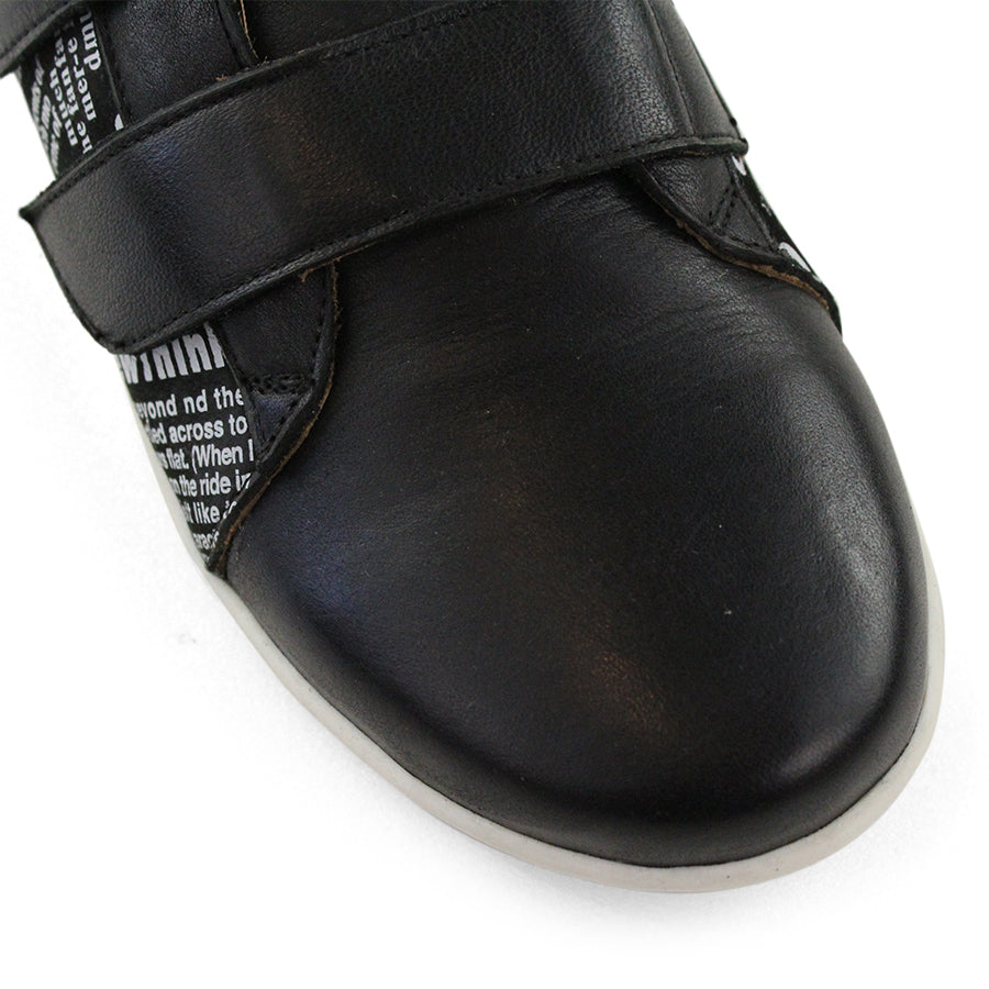 FRONT VIEW OF BLACK NEWSPAPER PRINT SNEAKER WITH TWO VELCRO STRAPS AND WHITE SOLE  