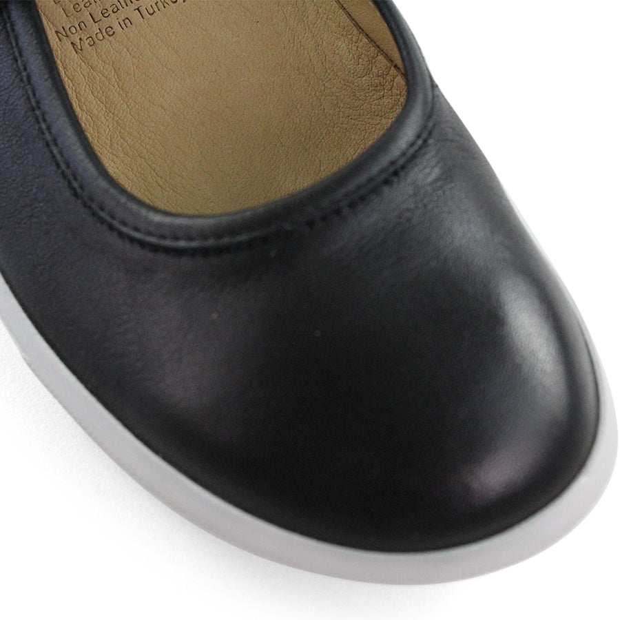 FRONT VIEW OF BLACK CASUAL SHOE WITH MARY JANE STYLE STRAP ACROSS THE TOP  AND WHITE STITCH DETAIL   