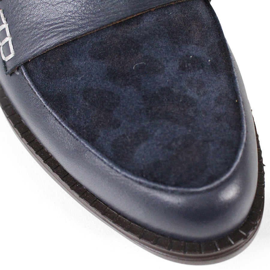 FRONT VIEW OF NAVY FLAT SHOE WITH LEOPARD PRINT FRONT PANEL AND STRAP WITH WHITE STITCH DETAILING 