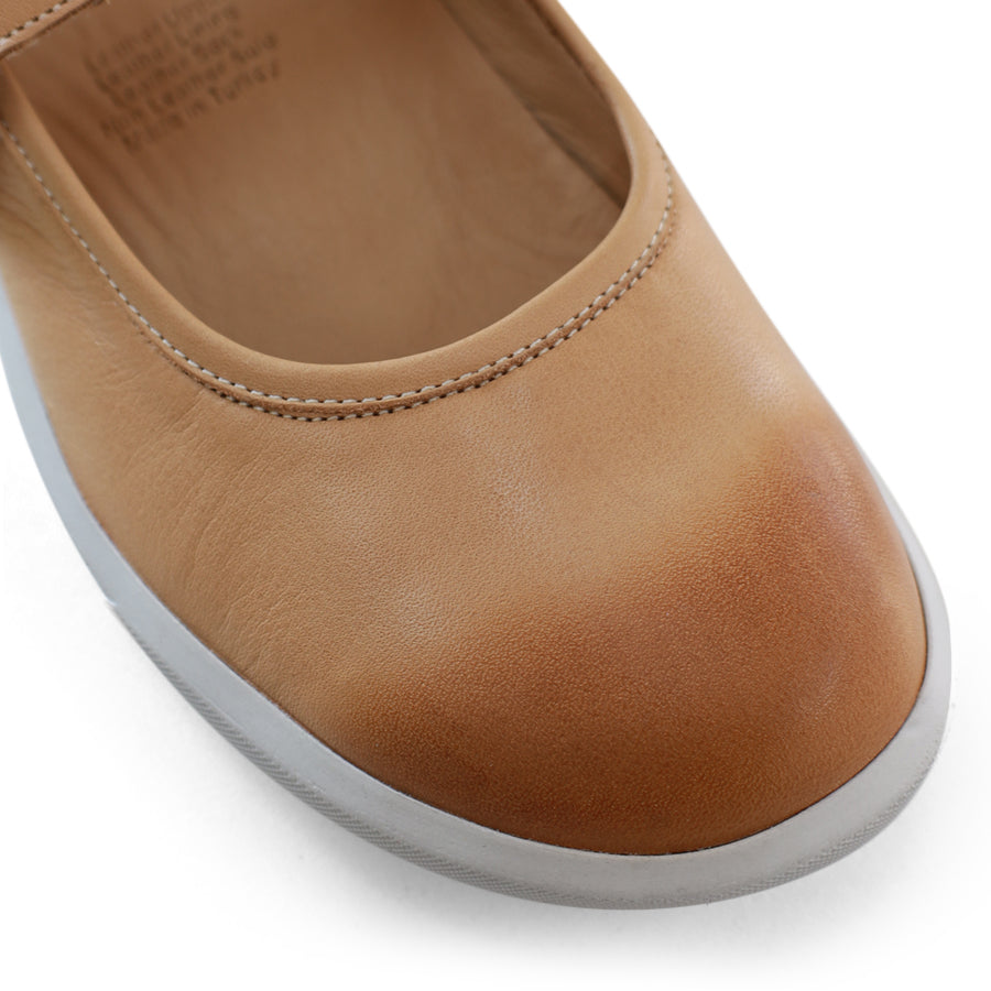 FRONT VIEW OF BEIGE CASUAL SHOE WITH MARY JANE STYLE STRAP ACROSS THE TOP  AND WHITE STITCH DETAIL   