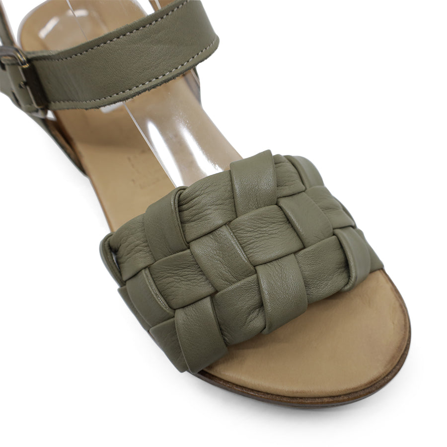 FRONT VIEW OF GREEN LEATHER STRAP SANDAL. FRONT STRAP INTERWOVEN PLAITED LEATHER. VELCRO ADJUSTABLE Y BACK WITH DECORATIVE BUCKLE