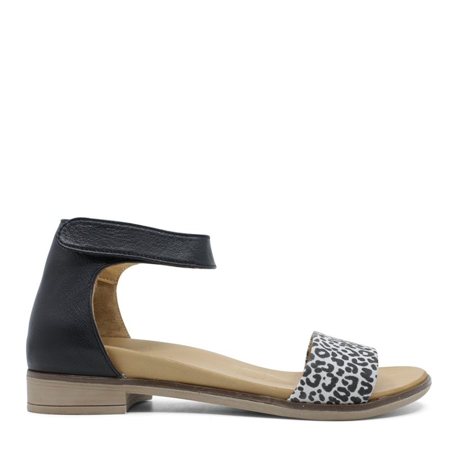 SIDE VIEW OF WHITE LEATHER SANDAL WITH LEOPARD PRINT DETAIL ON FRONT AND VELCRO STRAP TO SECURE 