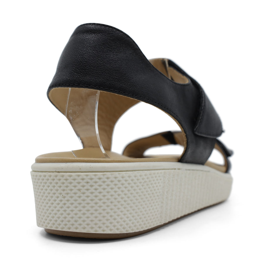 BACK VIEW OF METALLIC BLACK SANDAL WITH TWO VELCRO STRAPS AND WHITE SOLE